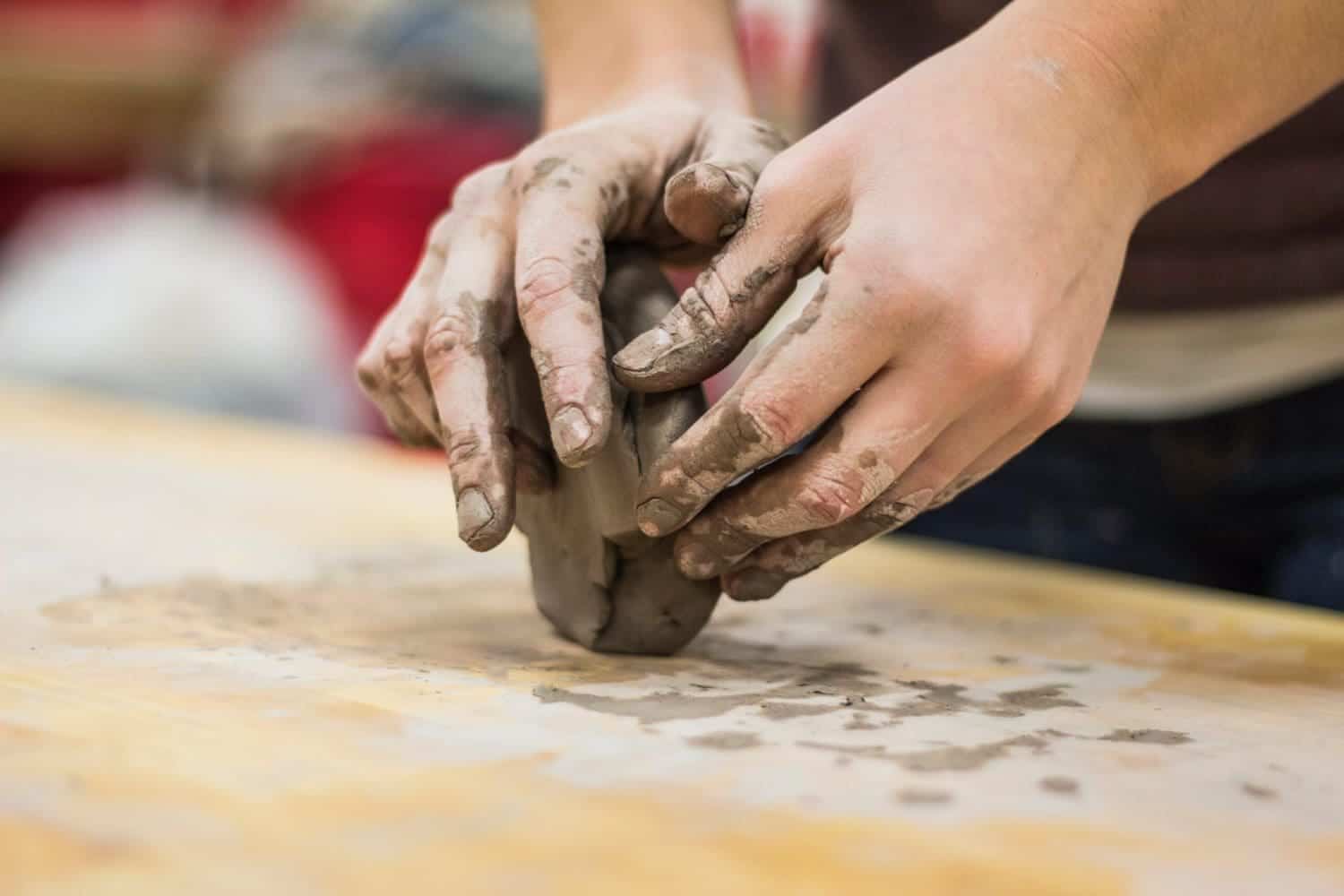 A close-up of a person making a sculpture from wet clay. An event is organized to create clay sculptures using a blindfold in Miami.