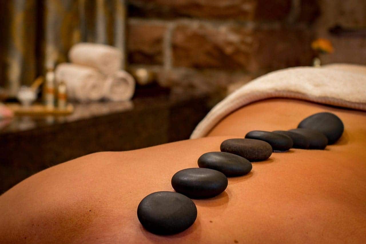 A close-up of a woman getting a stone massage with dimmed lights in the background.