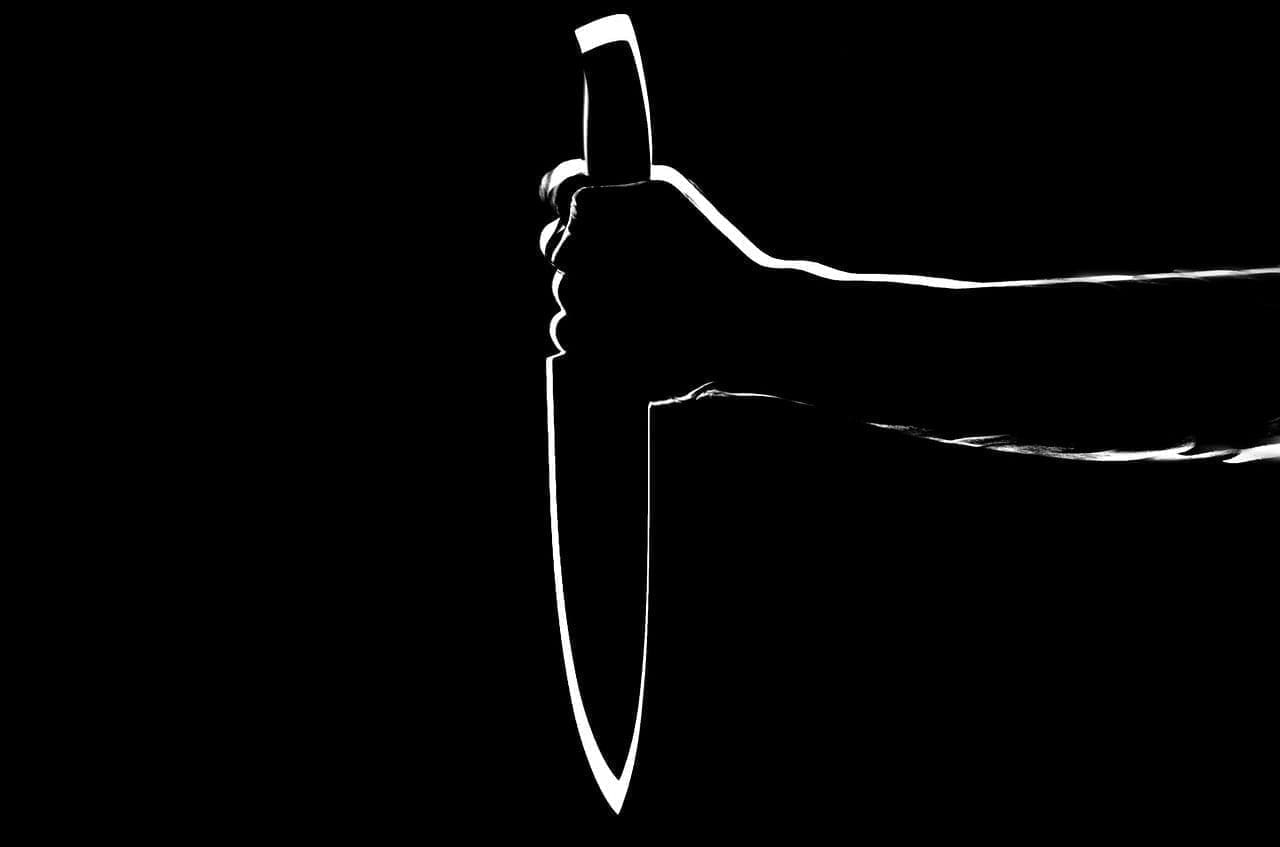 Silhoutte of someone holding a knife to kill in the dark.