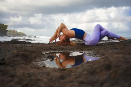 Woman practicing yoga on Hawaiian beach at sunset.
